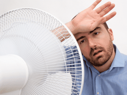 man sitting in front of fan because AC is broken