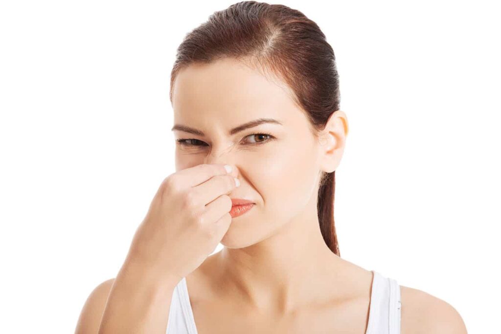 woman pinching nose because air inside home smells